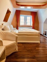 A modern bedroom with a large bed, a chair, and a window with curtains.