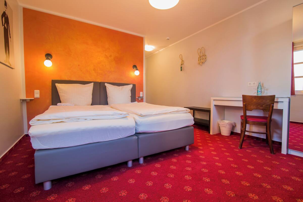 A hotel room with a double bed, a desk, and a chair.