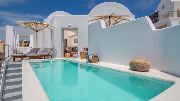 A pool area with white walls, lounge chairs, and umbrellas. - Villa - Sleeps 3 - Private Pool-parking (Santorini)