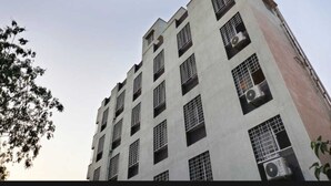 Ein mehrstöckiges Gebäude im modernen Architekturstil, mit einer Reihe von Fenstern und Klimaanlagen an der Außenwand.