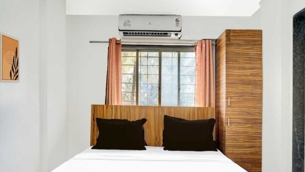 Ein Hotelzimmer mit einem Bett, einer Klimaanlage, einem Vorhangfenster und einem Holzschrank.