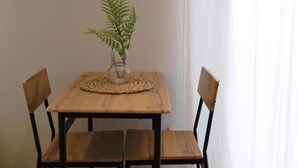 Ein Holztisch mit einer Glasvase, die ein Farn enthält, und zwei Holzstühle davor.