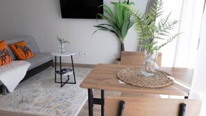Uma sala de estar com sofá, mesa de centro e televisão na parede.