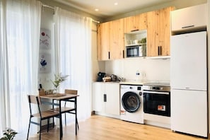 A compact kitchen with wooden cabinets, a washing machine, an oven, and a refrigerator. - R&K Apartment Madrid - Deluxe Apartment in the heart of the city (Madrid)