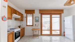 Cocina compacta con armarios de madera, horno empotrado, una mesa pequeña y un refrigerador.