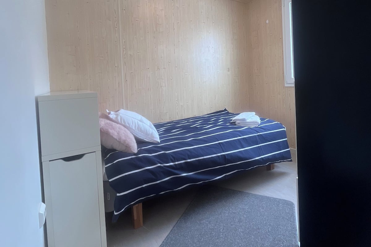 A small, compact room with a single bed, a small cabinet, and a window.