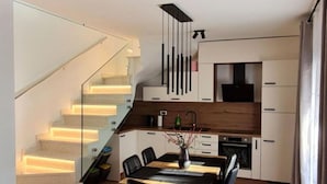 A modern kitchen with a dining area, wooden flooring, and a staircase with illuminated steps. - House With Private Jacuzzi Near Umag (Umag)