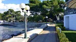 A waterfront promenade with stone steps, lamp posts, and a white building with a covered area. - House With Private Jacuzzi Near Umag (Umag)