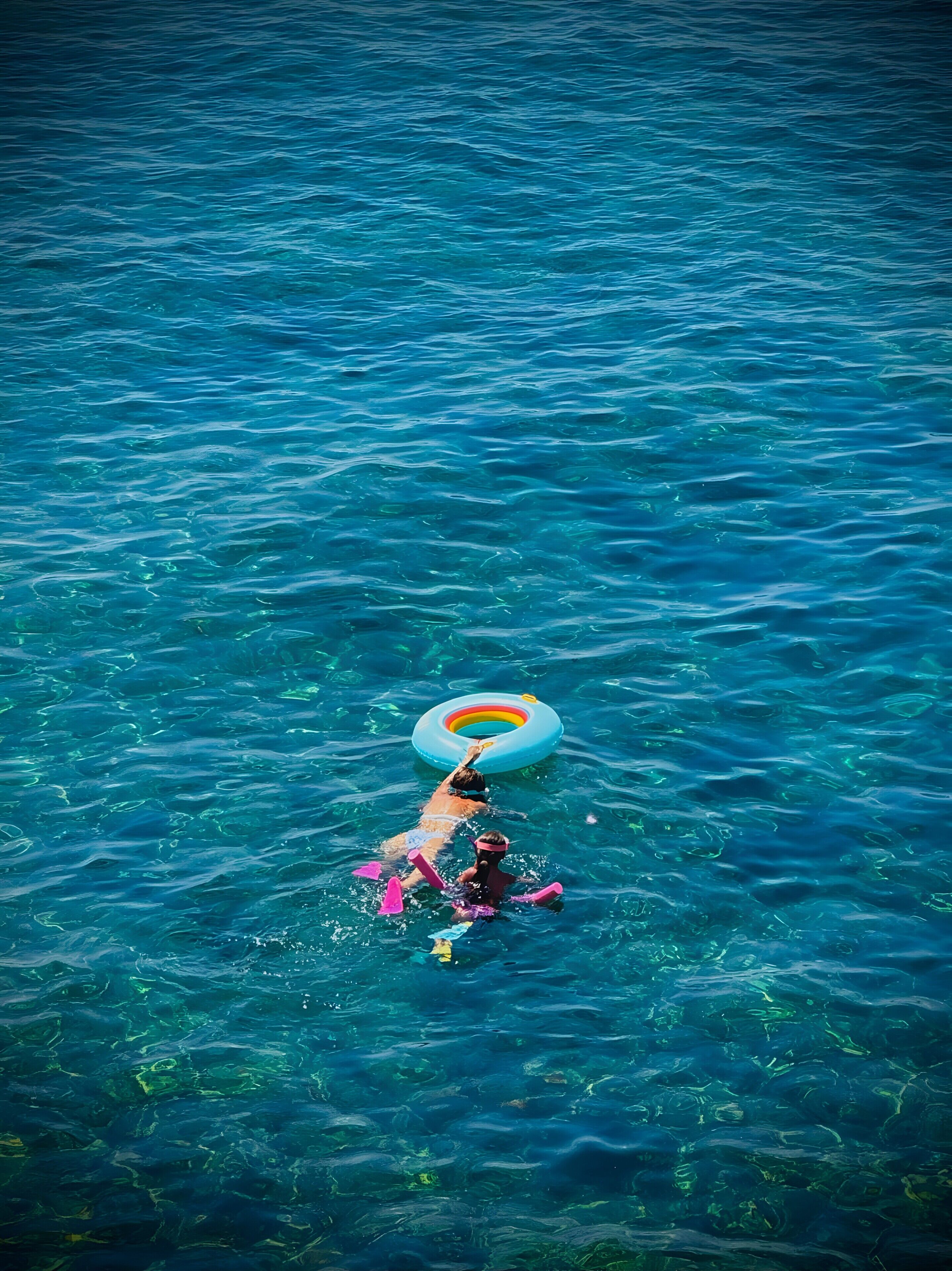 A person floating in clear blue water with a ring float.