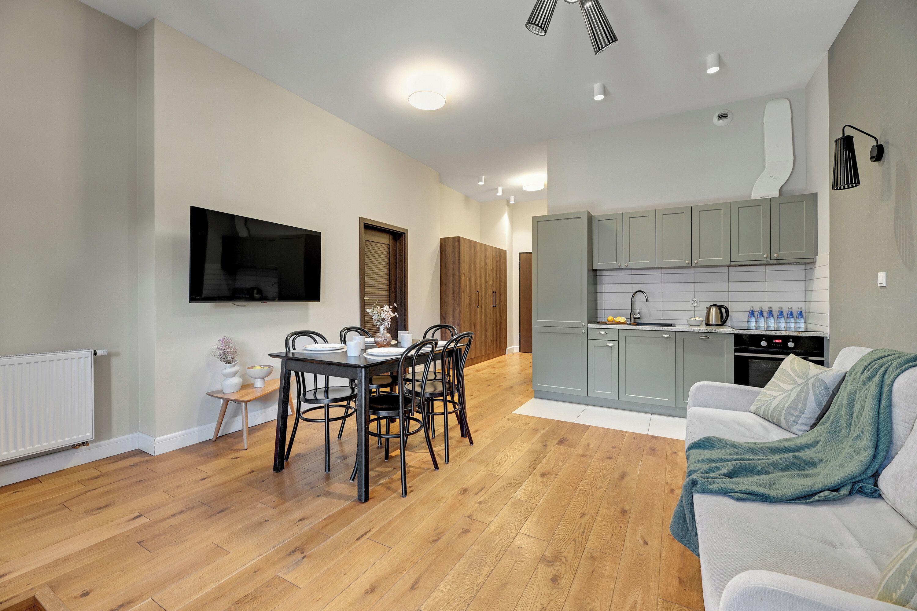 A modern kitchen with grey cabinets, a built-in oven, and a sink.