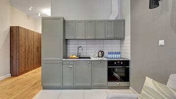 Eine moderne Küche mit grauen Schränken, Holzboden und eingebautem Backofen.