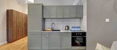 A modern kitchen with grey cabinets, a wooden floor, and a built-in oven.