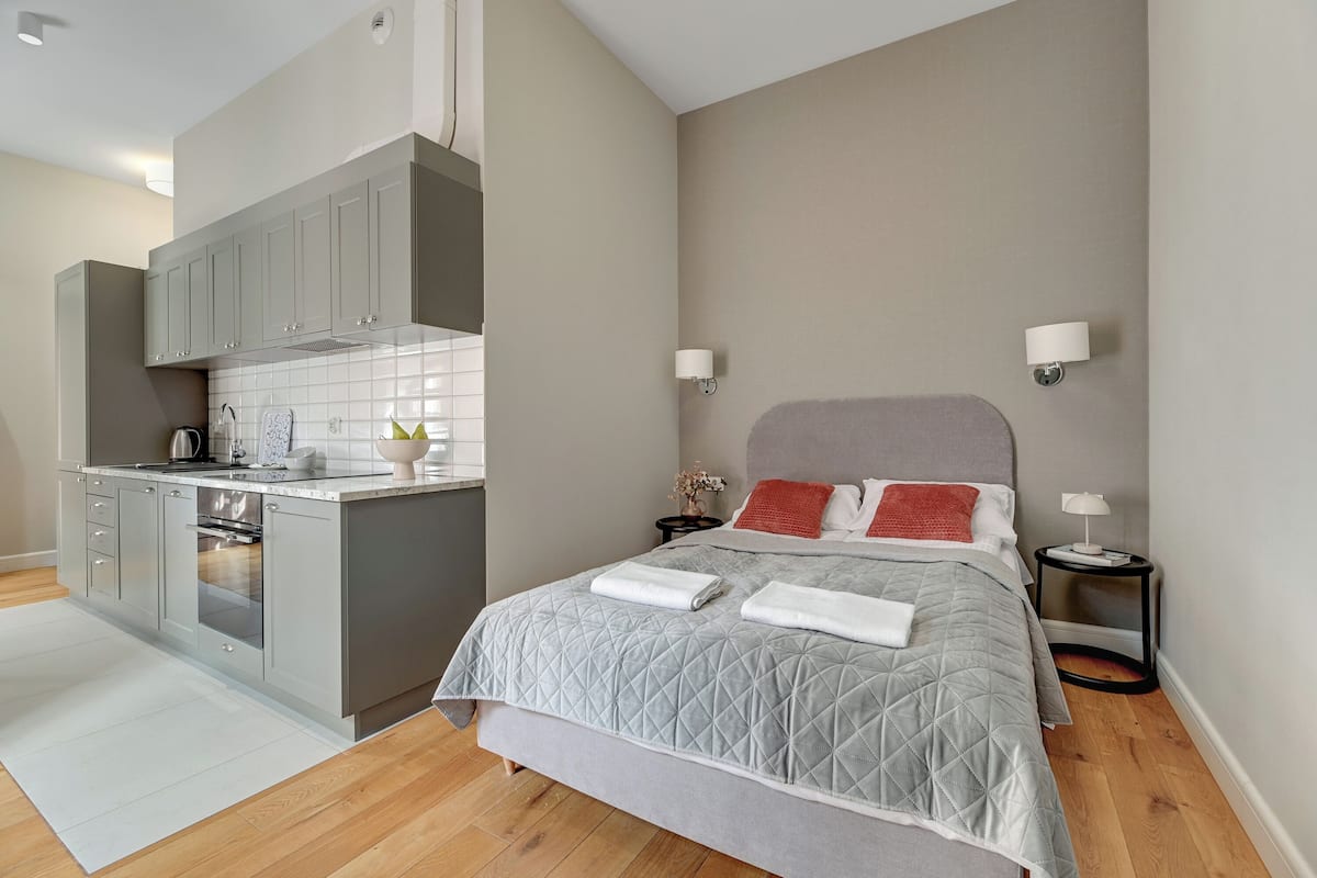 Ein modernes Hotelzimmer mit einem grauen Bett, einer kleinen Küchenzeile und einem grauen Kleiderschrank.