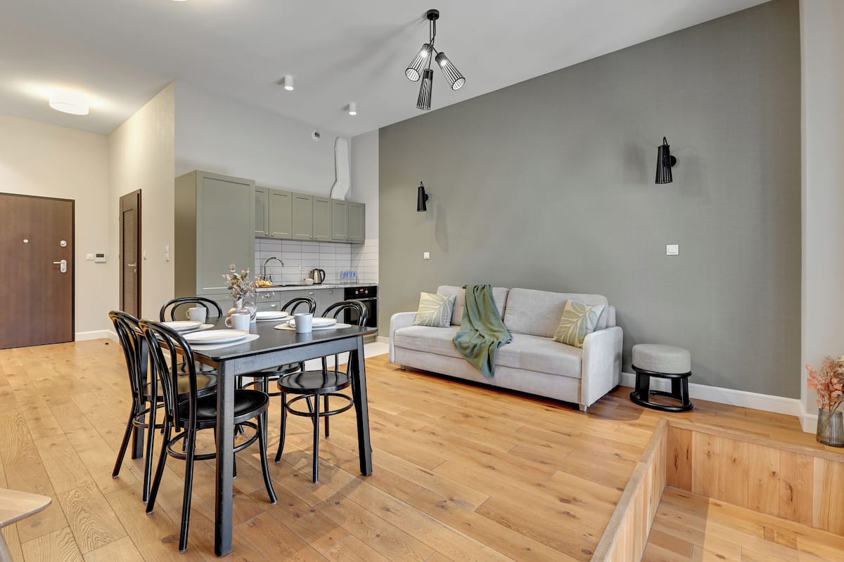 Eine moderne Küche mit Essbereich, grauer Wand und weißem Sofa.