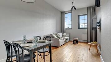 Una sala de estar moderna con comedor, un sofá y una pequeña mesa con un cuenco de limones.