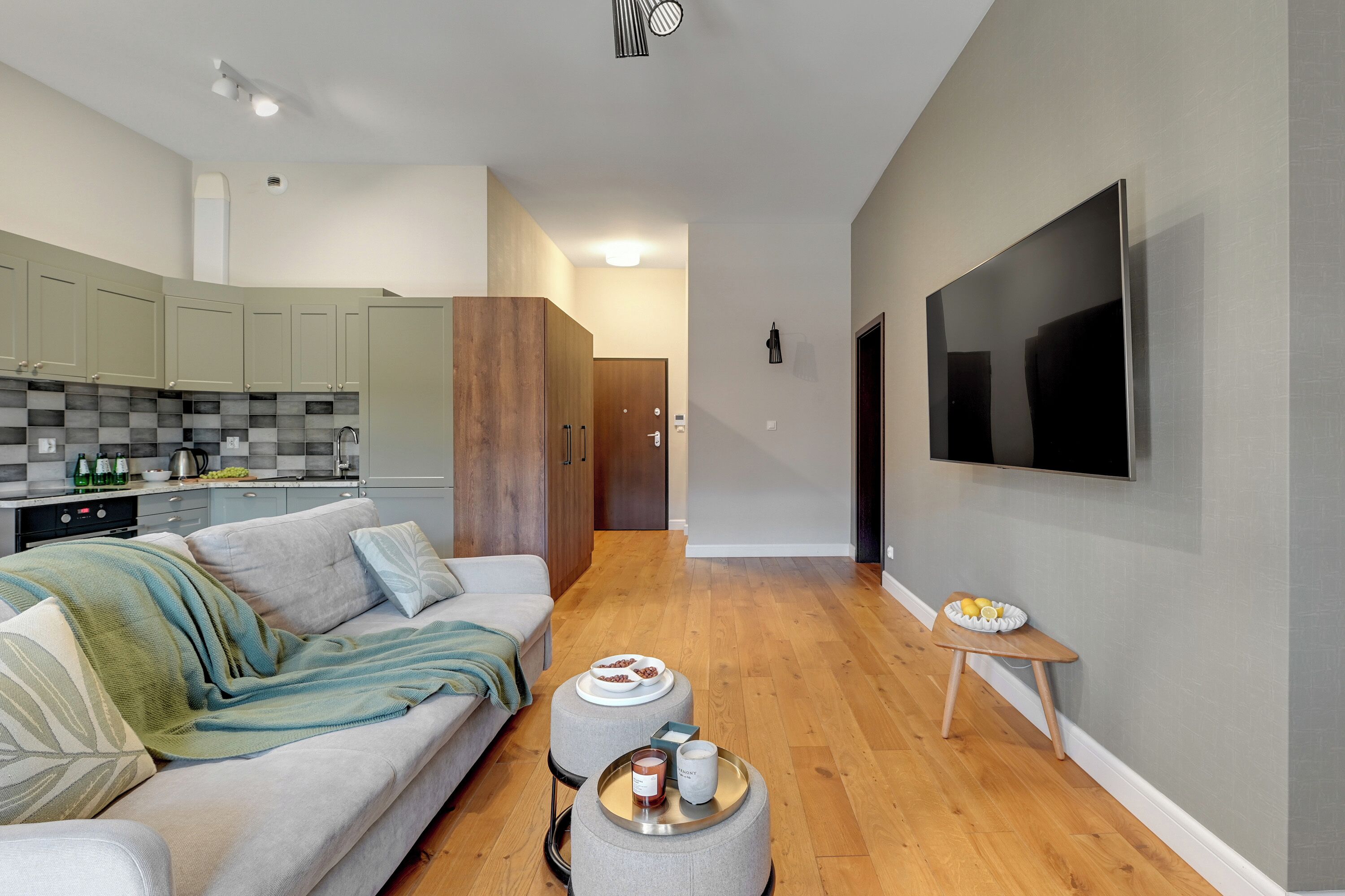 A modern living room with a grey sofa, a coffee table, and a TV mounted on the wall.