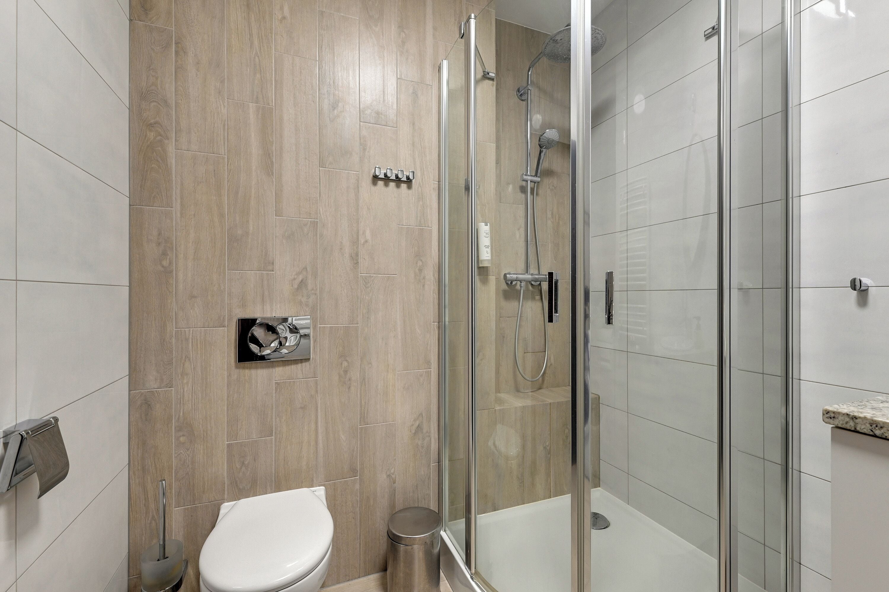 A modern bathroom with a glass-enclosed shower, a toilet, and a sink.