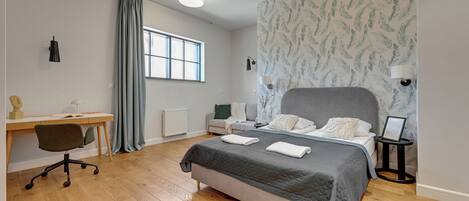 Un dormitorio con una cama, un escritorio, una silla, un ventanal y una pared con diseño.