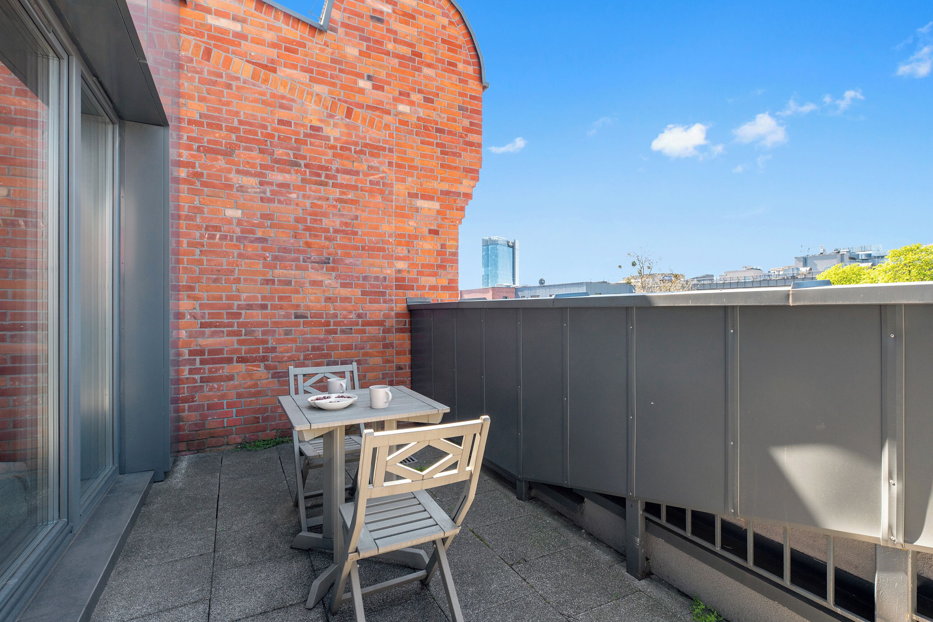 A patio with a table and chairs, a brick wall, and a view of the city skyline.