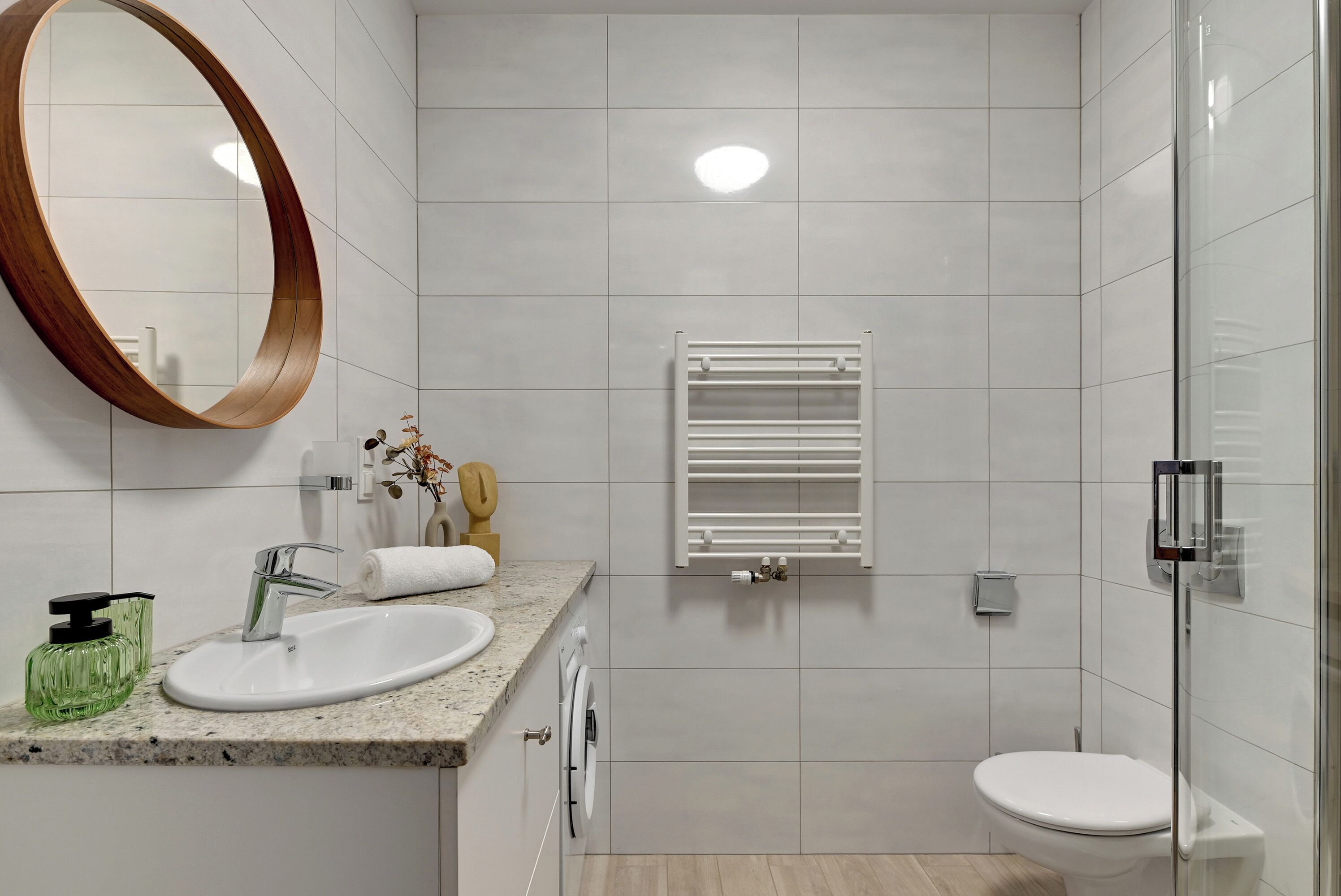 A modern bathroom with a sink, mirror, towel rack, and toilet.
