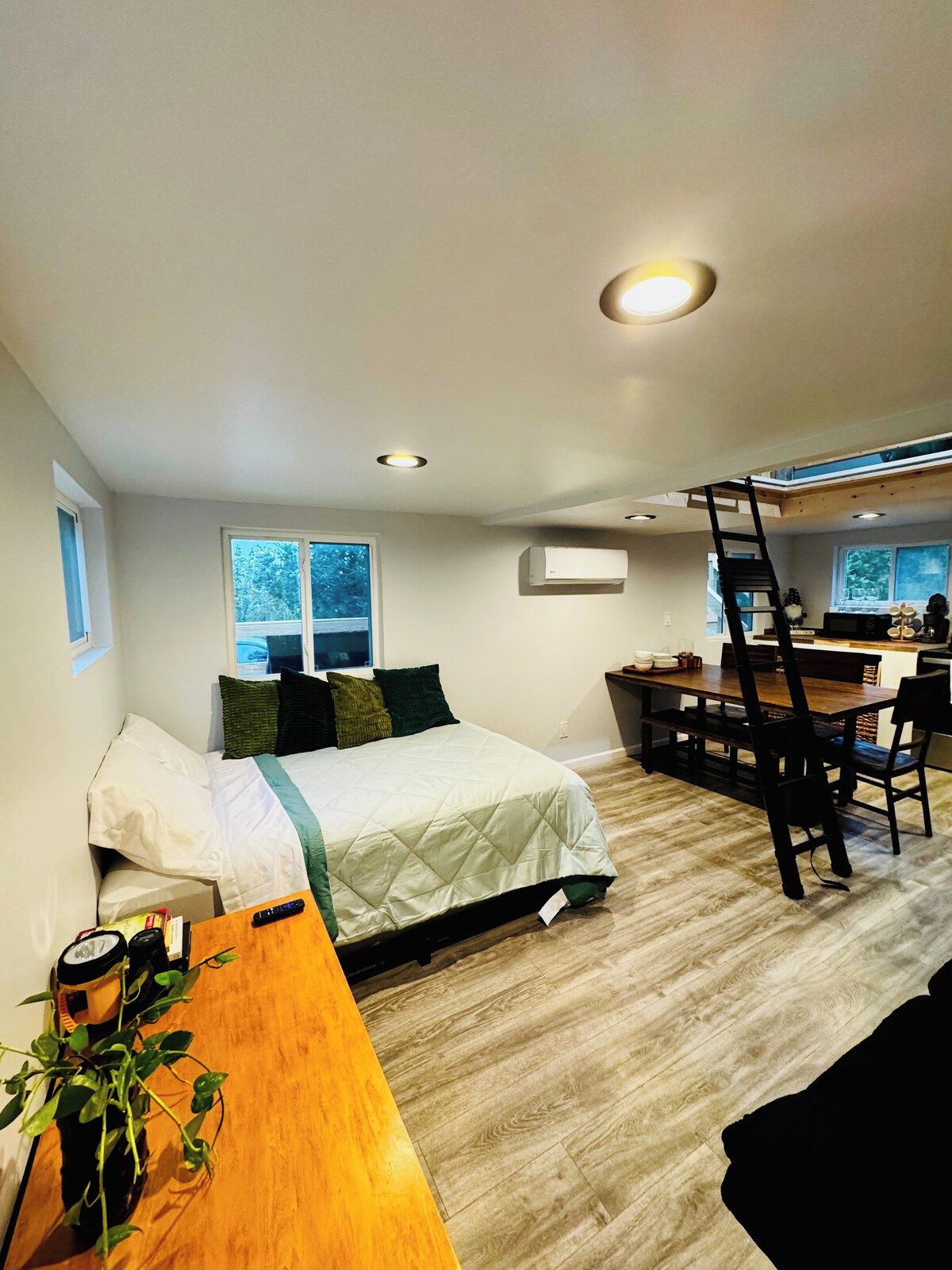 Una habitación pequeña con cama, mesa de comedor y una escalera que sube a un nivel superior.