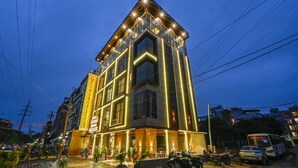 A modern hotel with a prominent corner entrance, large windows, and a well-lit facade. - Hotel Grand Girdhar Premier (Indore)