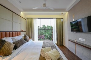 A hotel room with a bed, a flat-screen TV, a ceiling fan, and a window with curtains. - Hotel Grand Girdhar Premier (Indore)