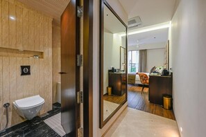 Un baño moderno con tocador de mármol, inodoro y un espejo grande.