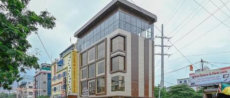 Un hotel moderno con fachada de vidrio, varios pisos y una entrada destacada.