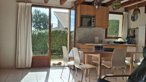 A spacious living area with a dining table, chairs, a sofa, and a kitchen in the background.