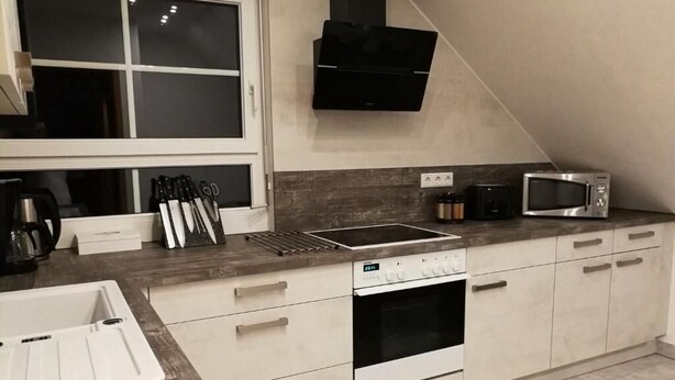 A modern kitchen with a built-in oven, microwave, and a window above the sink. - Deluxe vacation apartment / near Willingen (Korbach)