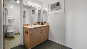 A bathroom with a wooden vanity, a mirror with lights, a toilet, and a shower area. - Premium Room, 1 Queen Bed, Lake View (Polson)