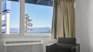 A room with a window, a chair, and a wall-mounted air conditioner. - Premium Room, 1 Queen Bed, Lake View (Polson)