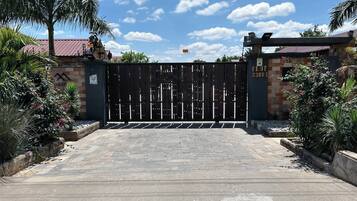 A gated entrance with a metal gate, a brick wall, and a sign indicating a plot number.
