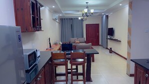A compact living space with a kitchenette, dining area, and a sofa set. - Upland Serviced Apartments (Lusaka)