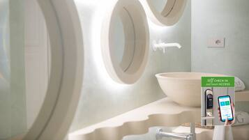 A modern bathroom with a large sink, a toilet, and a self-check-in kiosk.