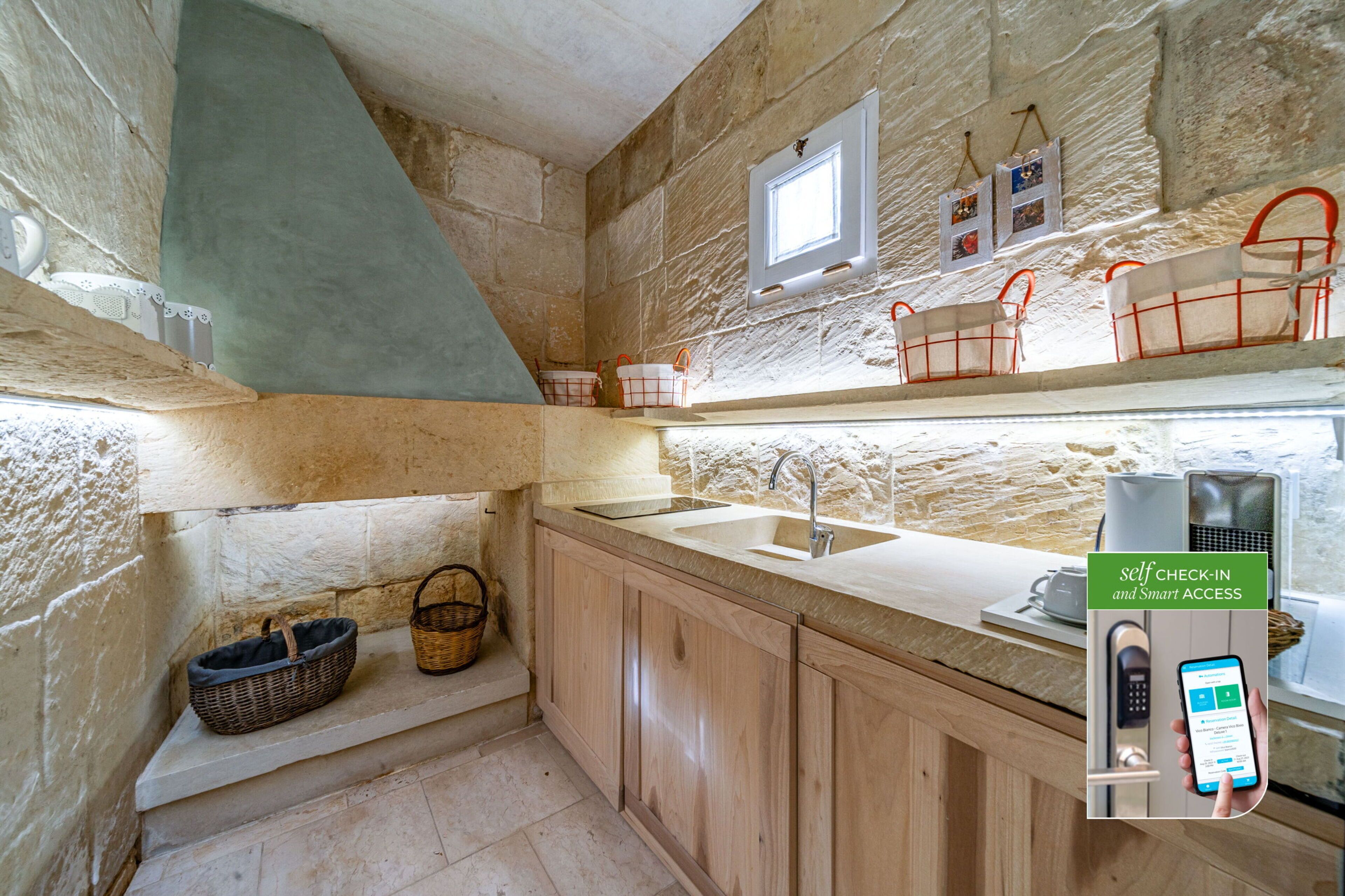 A kitchen with stone walls, wooden cabinets, a built-in sink, and a window.