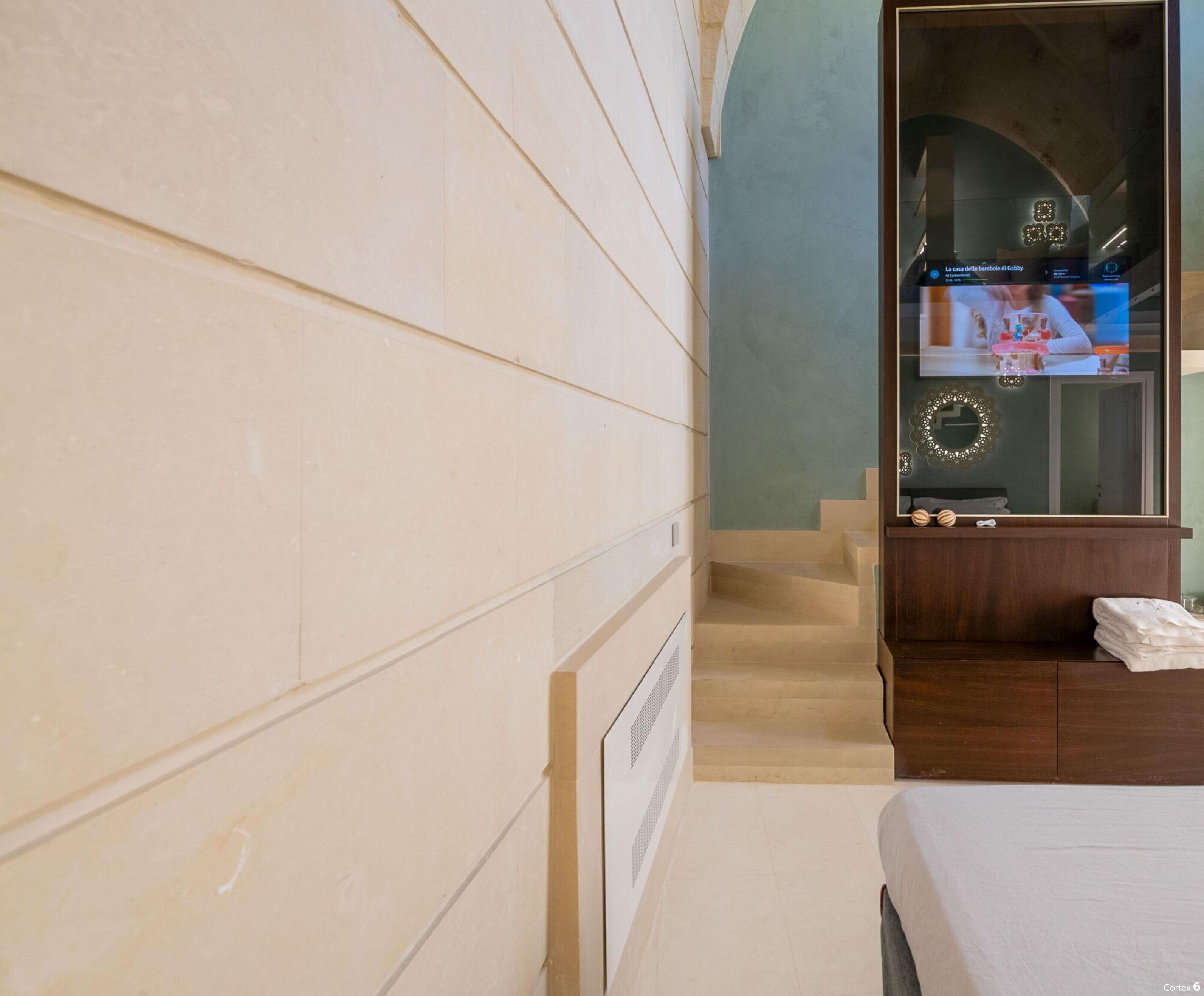 Habitación de hotel con cama, un pequeño rincón de estar, televisor y una escalera que lleva a un nivel superior.