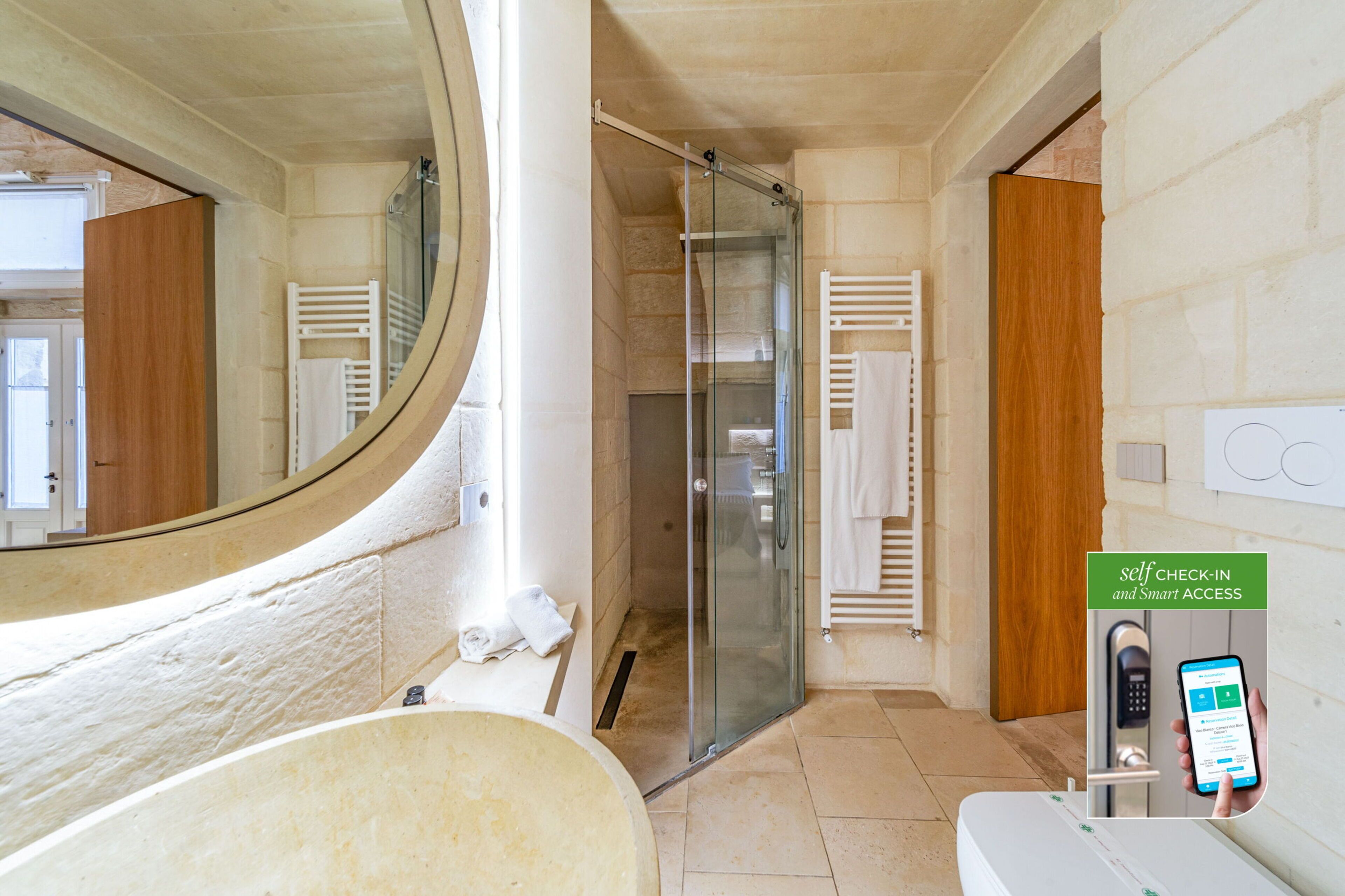 A modern bathroom with a glass shower enclosure, a large mirror, and a self-check-in kiosk.