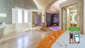 A luxurious hotel room with a stone arch ceiling, a large mirror, a bathtub, and a self-check-in kiosk. - Corte Dei Granai Meeting&SPA Raro Rooms (Maglie)