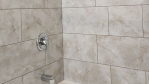 Une salle de bain avec une baignoire, une douche et des murs carrelés.
