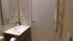 A modern bathroom with a white sink, mirror, and towel rack.