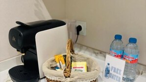 A coffee maker, a basket with items, and two water bottles on a counter.
