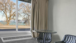 Ein Zimmer mit großem Fenster, einem Tisch, zwei Stühlen und einer Wand-Klimaanlage.