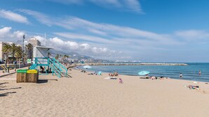 Una playa con una torre de salvavidas, sombrillas y gente relajándose.