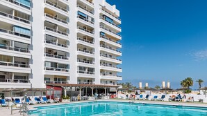 Un hotel con piscina, varios balcones y vista al mar.