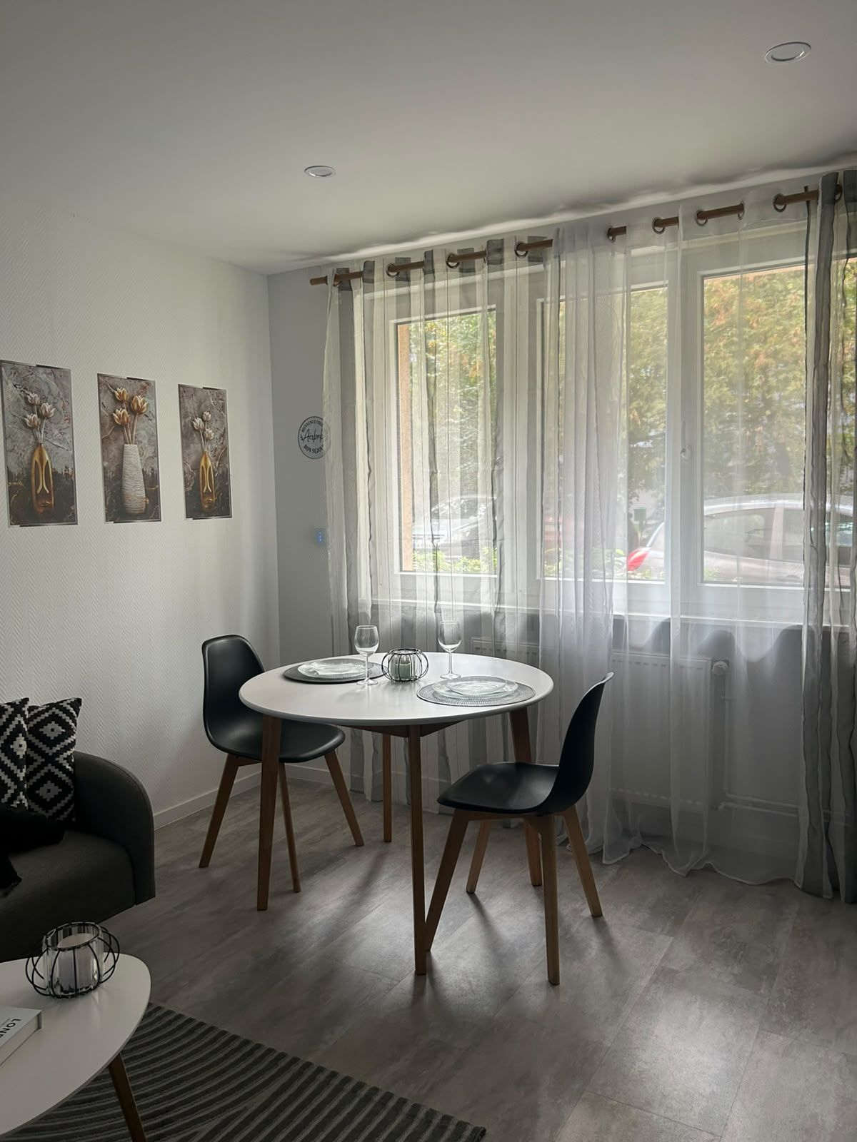 Un coin repas avec une table ronde, quatre chaises et une fenêtre avec des rideaux.