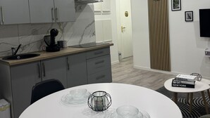 A modern kitchen with grey cabinets, a built-in stove, and a white dining table with glassware. - Appart'Cosy• Near Mulhouse -FREE WIFI-Easy parking (Illzach)