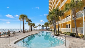 A pool area with a clear blue pool, palm trees, and a beach view. - Its Sea-esta Time! Sleep, Sun, & Sea on the 9th Floor! Sleeps 6! Beachfront! (Panama City Beach)