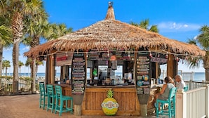 A tiki bar with a thatched roof, wooden counter, and menu boards. There are turquoise chairs and a pineapple decoration. - Its Sea-esta Time! Sleep, Sun, & Sea on the 9th Floor! Sleeps 6! Beachfront! (Panama City Beach)